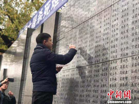 10日晨，下著小雨。南京大屠殺幸存者、死難者遺屬、學(xué)生們依次描寫名字，祭悼南京大屠殺遇難同胞。淡淡的墨汁摻著雨水，滲入了刻在紀念館灰色厚重石壁上的黑色名字中?！≈鞎苑f 攝